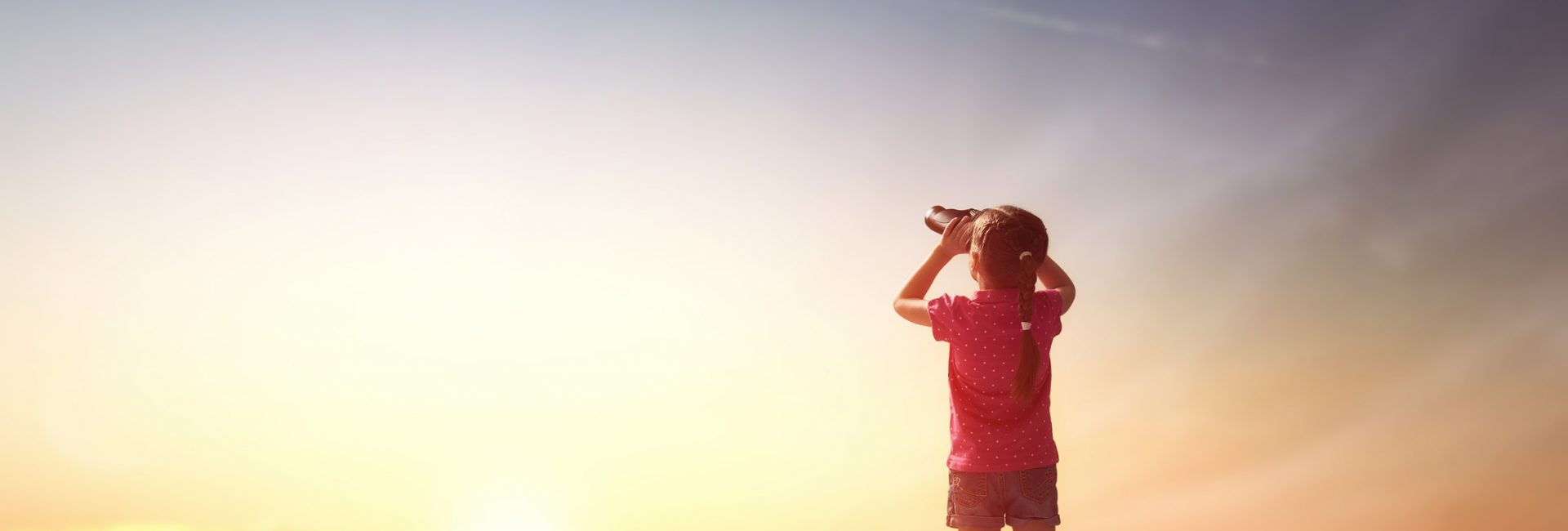 Cute little child girl looking through binoculars to the sky and flying plane.